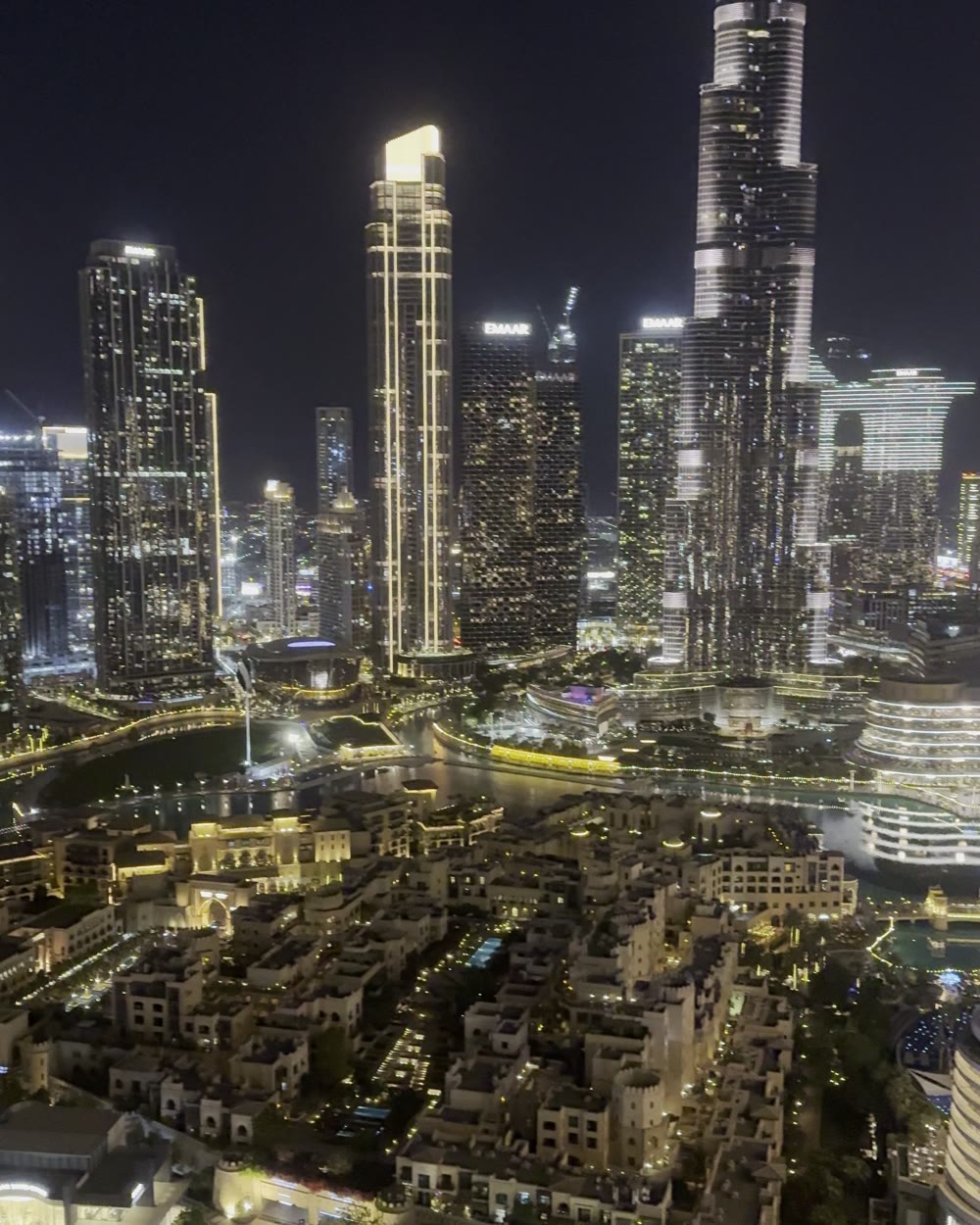 An aerial view of Downtown Dubai at night, with the Burj Khalifa and a canal of lit buildings