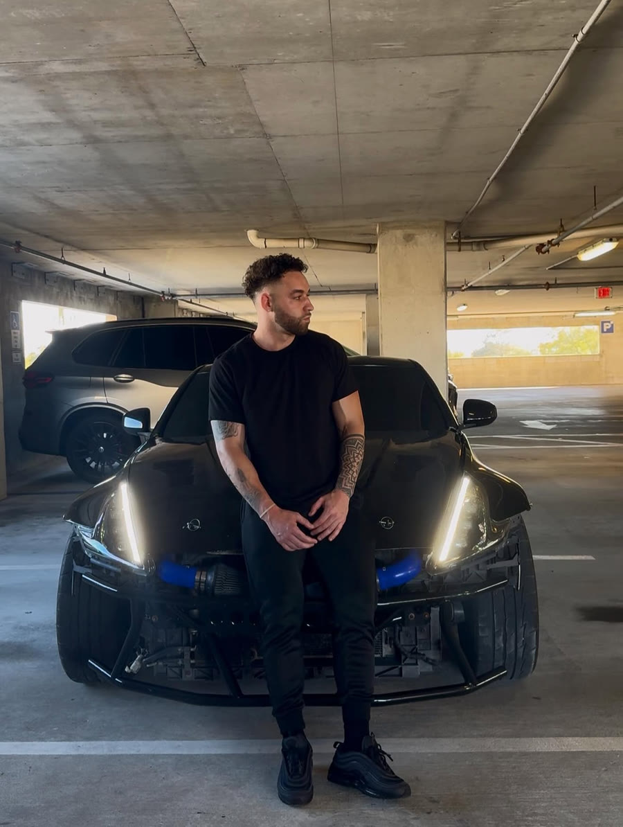 Tyler standing in front of his car in a parking garage